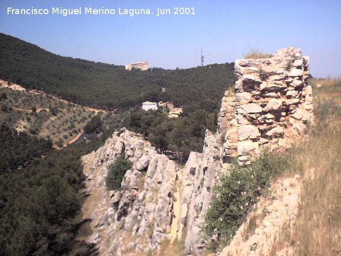 Castillo de Abrehuy - Castillo de Abrehuy. Acantilado de piedra y restos de muro sobre l, al fondo el Neveral y abajo la carretera de acceso